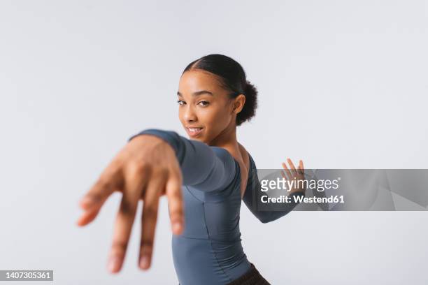 smiling young dancer practicing ballet against white background - ballerinas stock-fotos und bilder