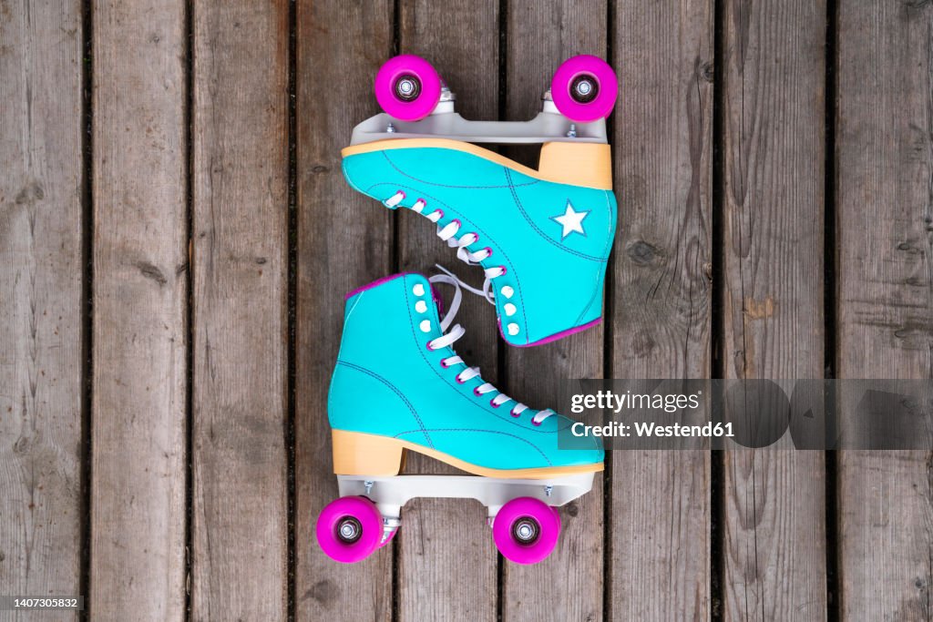 Multi colored roller skates on floorboard