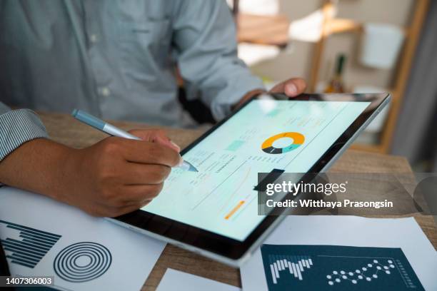 man analyzing statistical business report on tablet pc - collection foto e immagini stock