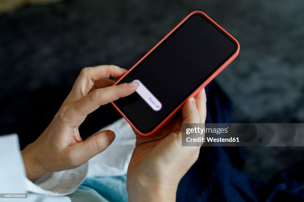 Woman turning off mobile phone at home
