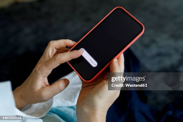 woman turning off mobile phone at home - turning on or off stock-fotos und bilder