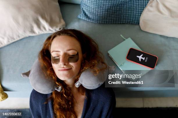 redhead woman leaning head on sofa with smart phone on airplane mode in living room at home - detox stock pictures, royalty-free photos & images