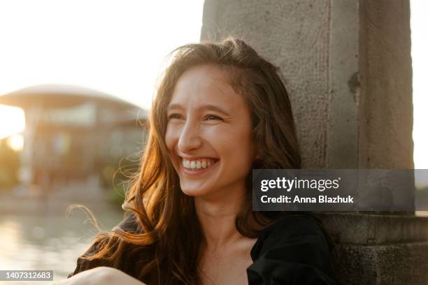 summer outdoors portrait on riverbank on sunset. young happy woman with long curly brown hair. soft warm sunlight at sunset in summer city. - caucasus fotografías e imágenes de stock