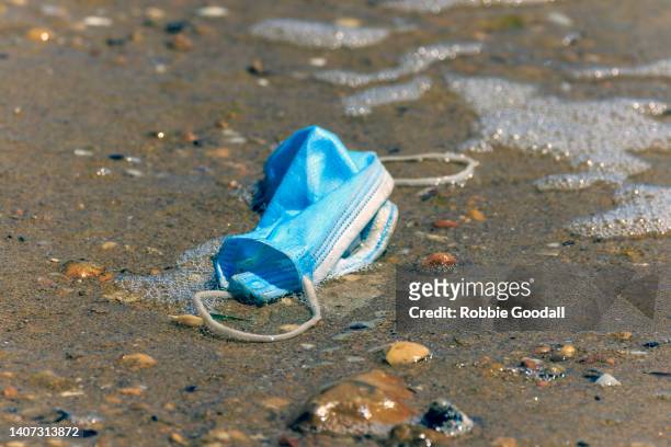 blue covid face mask polluting a sandy beach - old fashioned australian beach foto e immagini stock
