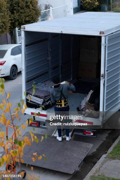 house moving process. owner and moving staff packing, protecting and transporting furniture and movables to moving truck - transporte de carga stock pictures, royalty-free photos & images