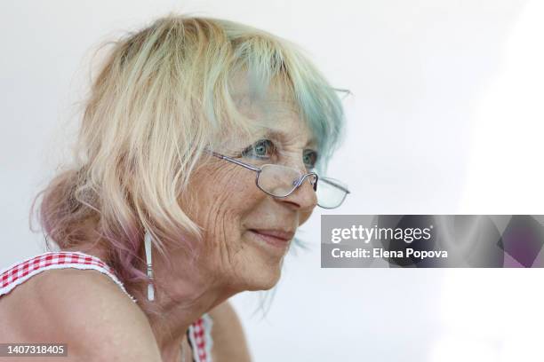 active seniors. confidence woman with colored blue hair strands smiling and looking away - frau haarsträhne blond beauty stock-fotos und bilder