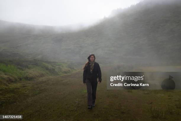 woman walking through foggy landscape - naderen stockfoto's en -beelden