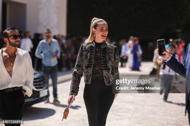 Chiara Ferragni wears gold earrings, a gold pendant necklace, a black lace print pattern high neck t-shirt, a black with embroidered white pattern...