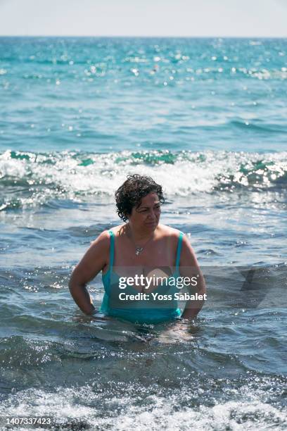 mature woman with curly hair sitting by the seashore - voluptuous mature women foto e immagini stock