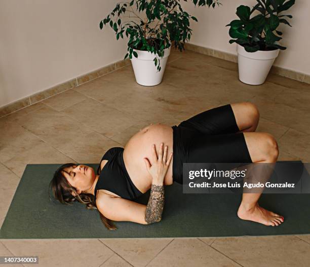 pregnant woman doing half bridge yoga in her home, cute pregnant woman doing setu bandha sarvangasana or half bridge yoga in her living room - setu bandha sarvangasana stock pictures, royalty-free photos & images