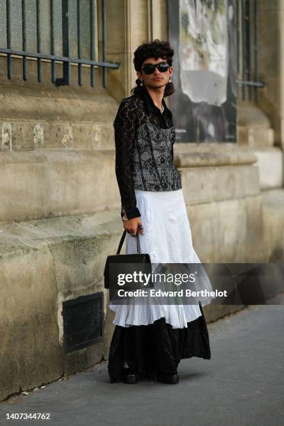 Guest wears black sunglasses, a black flower print pattern long sleeves shirt, a white shoulder-off ruffled midi dress, a black lace print pattern...