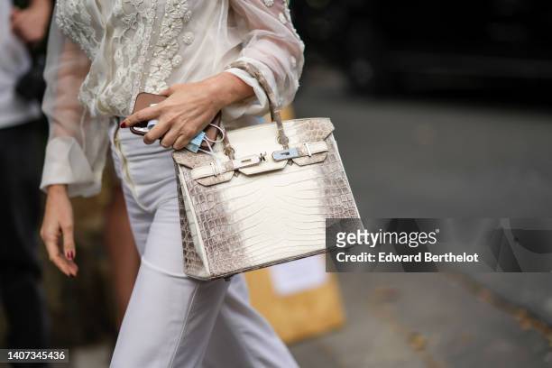 Guest wears a white silver with embroidered pearls and lace pattern shirt, a white shoulder-off top, white denim jeans large pants, a white and beige...