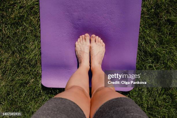 human feet are standing on a yoga mat on the lawn close-up - ponto de vista - fotografias e filmes do acervo