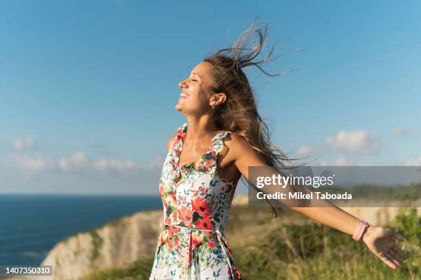 happy woman enjoying freedom on cliff near sea - comunidad autónoma del país vasco fotografías e imágenes de stock