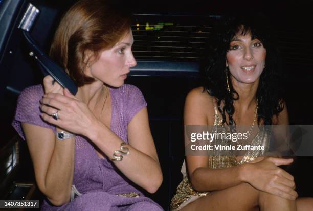 Cher sits beside her secretary in the backseat of a car, circa 1970.
