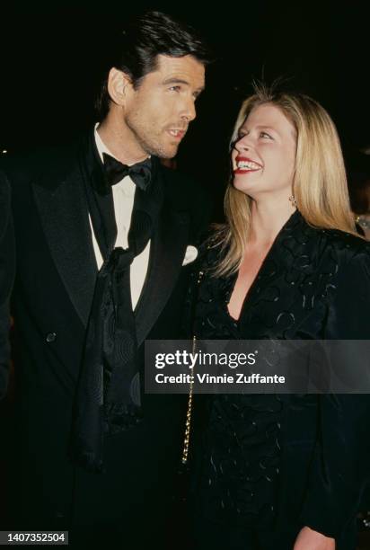 Pierce Brosnan in a black suit and bow tie speaks with adopted daughter Charlotte Brosnan at the 49th Annual Golden Globe Awards, held at the Beverly...