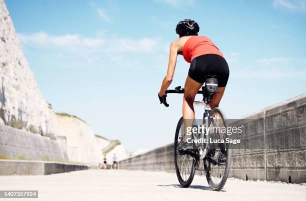 female cyclist on a seafront cycle in the sunshine - only mature women stock pictures, royalty-free photos & images