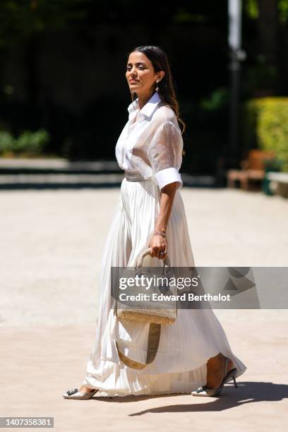 Guest wears pink gold pendant earrings from Van Cleef and Arpels, a white transparent short sleeves silk t-shirt, a white latte pleated long dress, a...