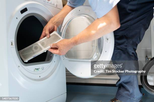a maintenance enginner is repairing a tumble dryer - filtración fotografías e imágenes de stock
