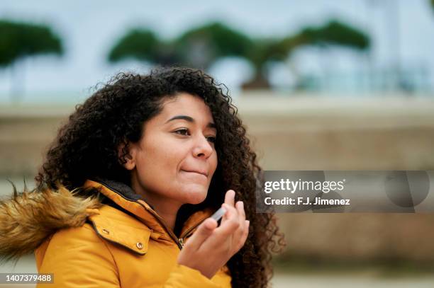 woman putting on lip protection in the street - winter skin stock pictures, royalty-free photos & images