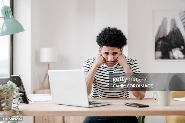 frustrated young man at home in front of his laptop - frustração imagens e fotografias de stock