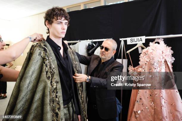 Designer Elie Saab prepares a model backstage prior to the Elie Saab Haute Couture Fall Winter 2022 2023 show as part of Paris Fashion Week on July...