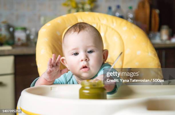 little baby is eating broccoli vegetable puree selective focus - baby food jar stock pictures, royalty-free photos & images