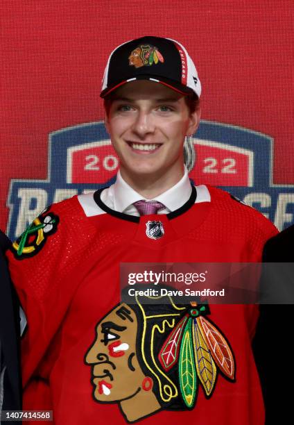 Kevin Korchinski poses for a photo onstage after being selected seventh overall by the Chicago Blackhawks during the first round of the 2022 Upper...