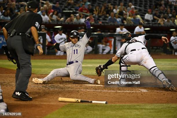 Jose Iglesias of the Colorado Rockies scores on a double by Randal Grichuk just ahead of the tag by Carson Kelly of the Arizona Diamondbacks during...