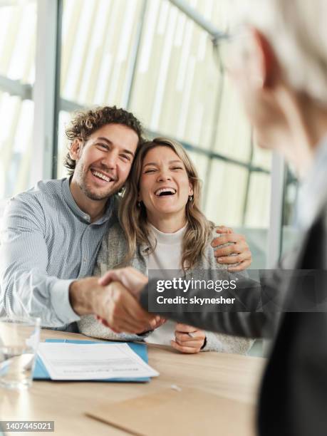 happy couple came to an agreement with their agent in the office. - life insurance stockfoto's en -beelden