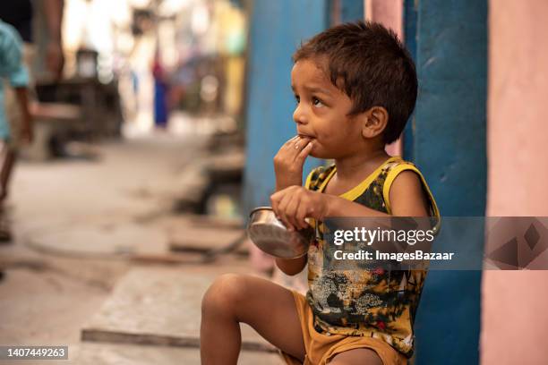 boy eating food at doorstep - indian slums fotografías e imágenes de stock