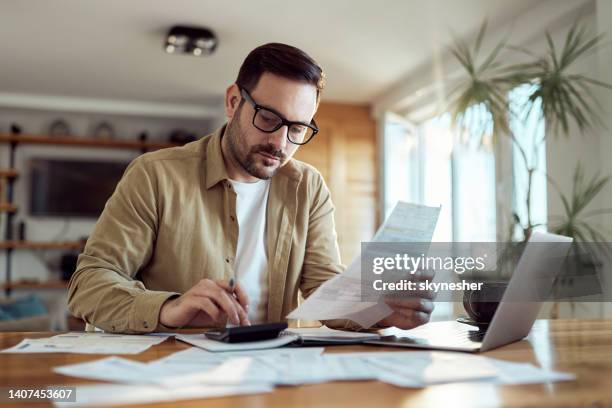 young man working on his financial bills at home. - rekenmachine stockfoto's en -beelden