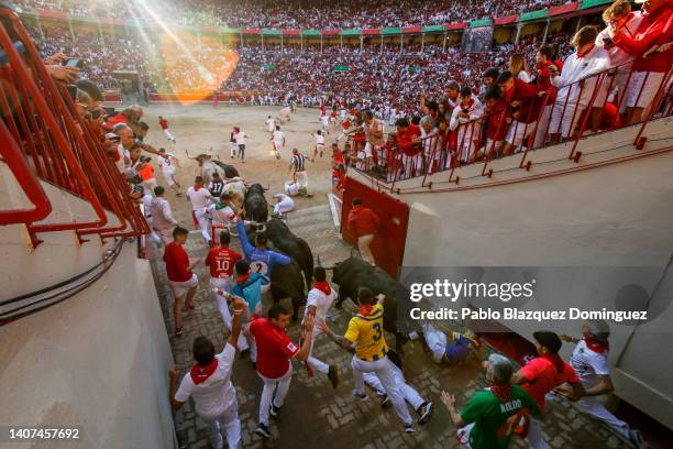 Revellers run with Fuente Ymbro's fighting bulls entering the bullring during the third day of the San Fermin Running of the Bulls festival on July...