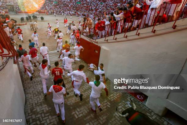 Revellers run with Fuente Ymbro's fighting bulls entering the bullring during the third day of the San Fermin Running of the Bulls festival on July...
