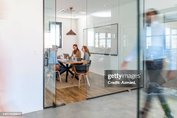 shot of business people walking right and left indoors while meeting is on the background - action laptop stock pictures, royalty-free photos & images