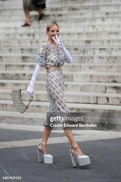 Leonie Hanne wears a gold large pendant earrings from Fendi, a beige with gray chain F monogram print pattern ruffled / puffy short sleeves / cropped...