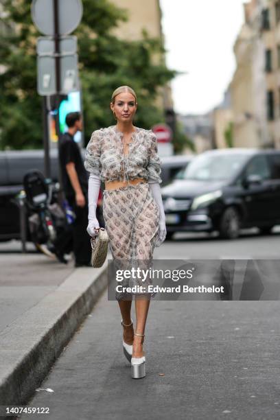 Leonie Hanne wears a gold large pendant earrings from Fendi, a beige with gray chain F monogram print pattern ruffled / puffy short sleeves / cropped...