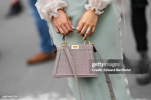 Jessica Wang wears a matching gold and rhinestones F pattern necklace, a beige silk cardigan form Fendi, a pale green silk V-neck / long tube dress,...