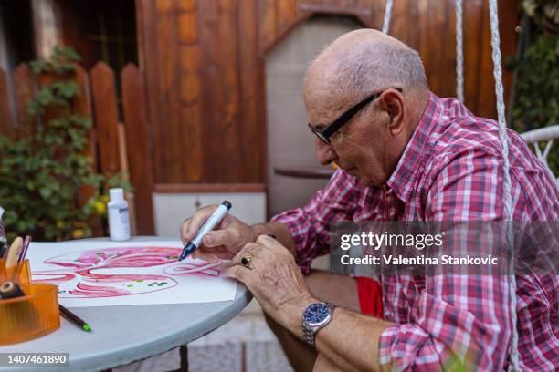 hombre jubilado que se enfoca en delinear elementos para la concientización sobre el cáncer de pulmón - cartoon cancer fotografías e imágenes de stock