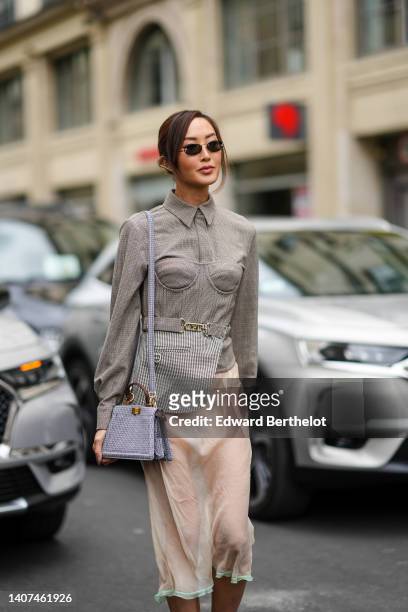 Chriselle Lim wears black sunglasses, a brown checkered print pattern jacket from Fendi, a matching brown and beige checkered print pattern corset /...