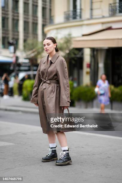 Guest wears silver earrings, a pink hair clip, a white pearls necklaces, a silver necklace, a brown oversized belted long trench coat, a brown suede...