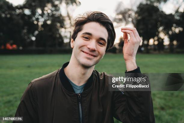 young adult man looking at camera while he's fixing his hair - man combing hair stock pictures, royalty-free photos & images