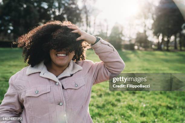 funny portrait of a young adult afro-american woman on a windy day - woman with hair blowing over face stock pictures, royalty-free photos & images