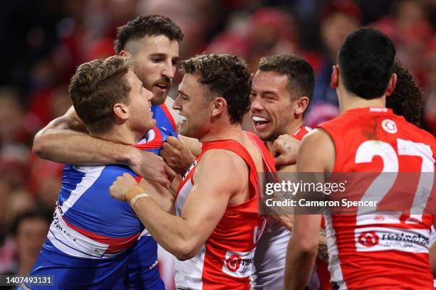 Lachie Hunter of the Bulldogs exchanges words with Will Hayward and Oliver Florent of the Swans during the round 17 AFL match between the Sydney...