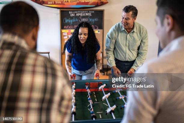 coworkers playing on a foosball table - ice breaker stock pictures, royalty-free photos & images