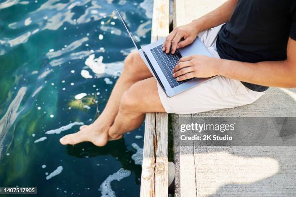 ein mann im urlaub sitzt auf einem steg am see in deutschland und arbeitet an seinem laptop - mobile worker stock-fotos und bilder