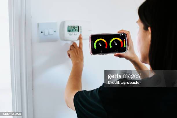 close up of woman holding smart energy meter in living room measuring energy efficiency - meter stock pictures, royalty-free photos & images
