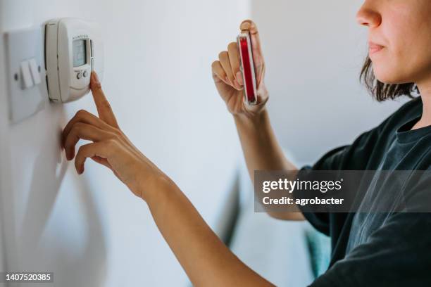 close up of woman holding smart energy meter in living room measuring energy efficiency - meter stock pictures, royalty-free photos & images