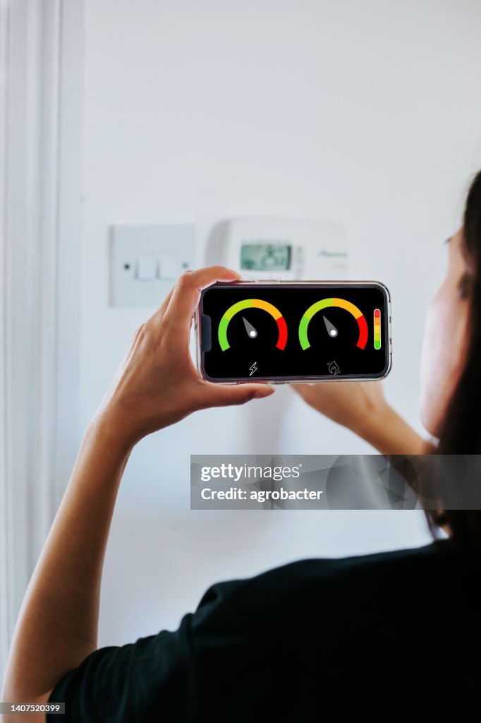 Close-up de mulher segurando medidor de energia inteligente na sala de estar medindo eficiência energética