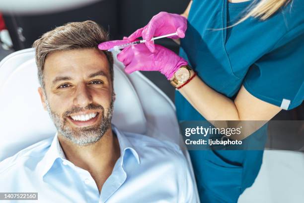 applying beauty injection for handsome bearded man in beauty salon - botox injection stock pictures, royalty-free photos & images